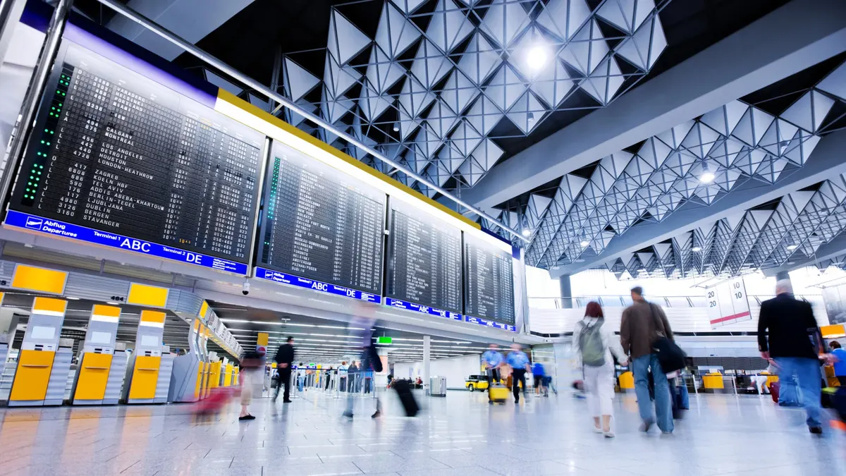 Busy airport terminal with departures board and travelers